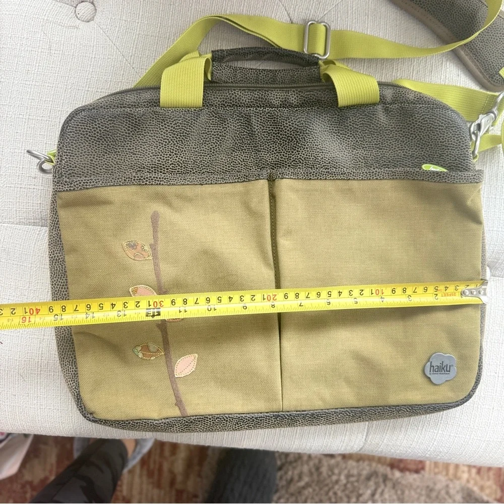 Haiku crossbody messenger/laptop bag with an embroidered leaf design.